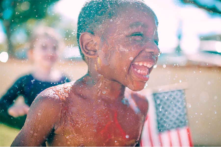 smiling boy getting splahed with water