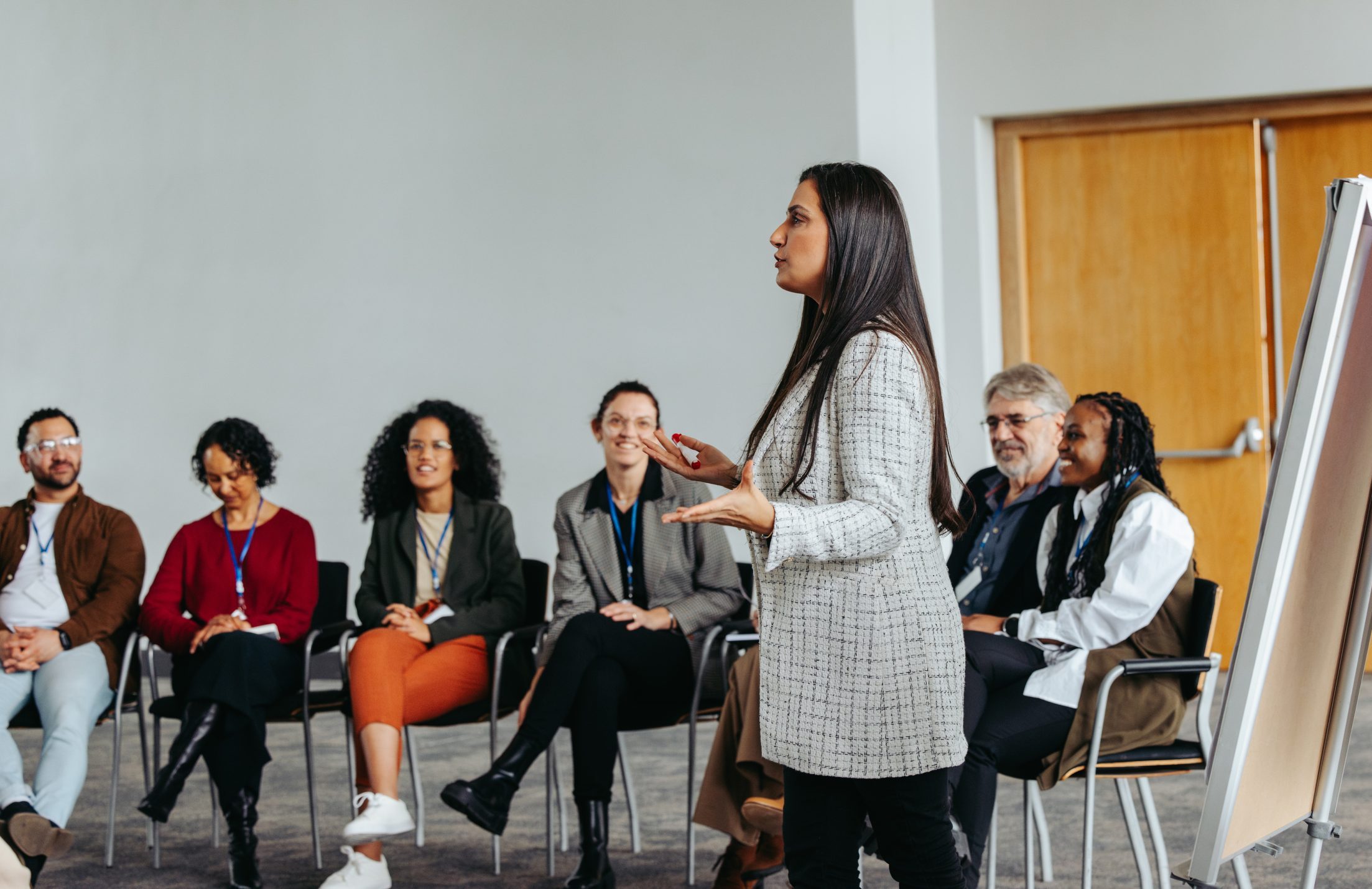 A female instructor engaging with a diverse team in a teambuilding session at a modern office, fostering collaboration and teamwork.
